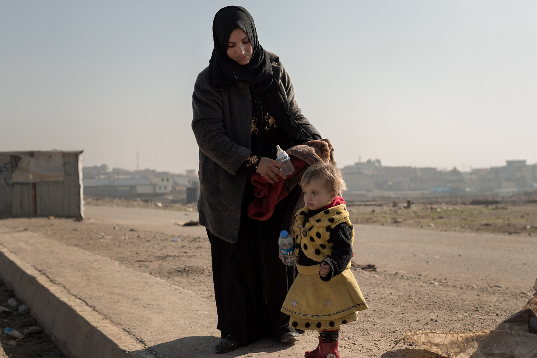 On the roadside between Al-Quds and Gogjali, a couple and their daughter escape from Al-Quds neighborhood, liberated three days ago, to a safer place farthest north of Kurdistan. Mosul, Iraq on Jan. 6, 2017. They lived with other Moslawis hidden from ISIS during two and a half years in the basement of a mosque and learned the arrival of the Iraqi Forces on Alghad FM. The husband, a former police officer, has been tortured by ISIS soldiers. They are relieved to be free but fear that ISIS could come back and make flee the Iraqi Forces again. 