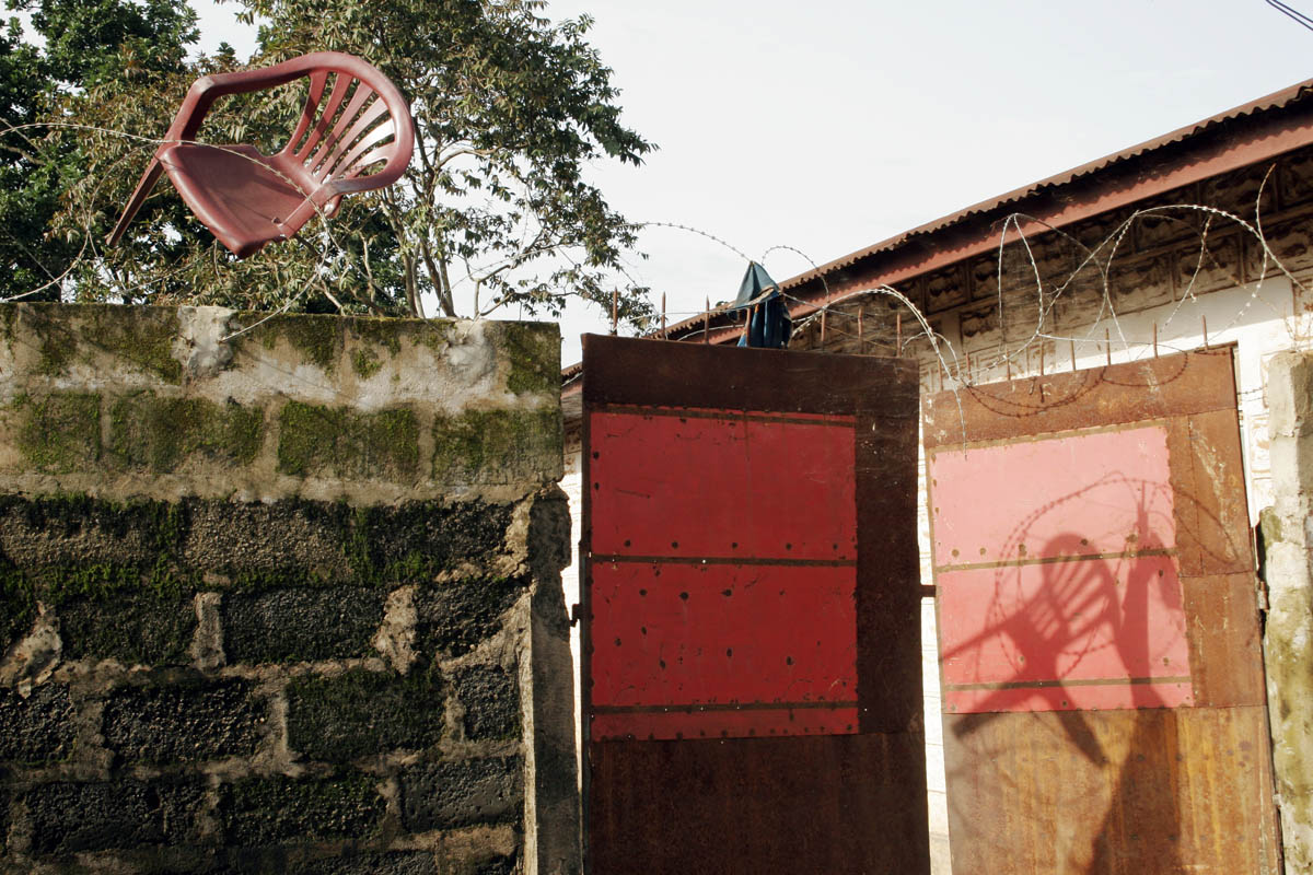 Barbed wire and a plastic chair top the wall around a home in Kenema, a town known for its diamond wholesale business.