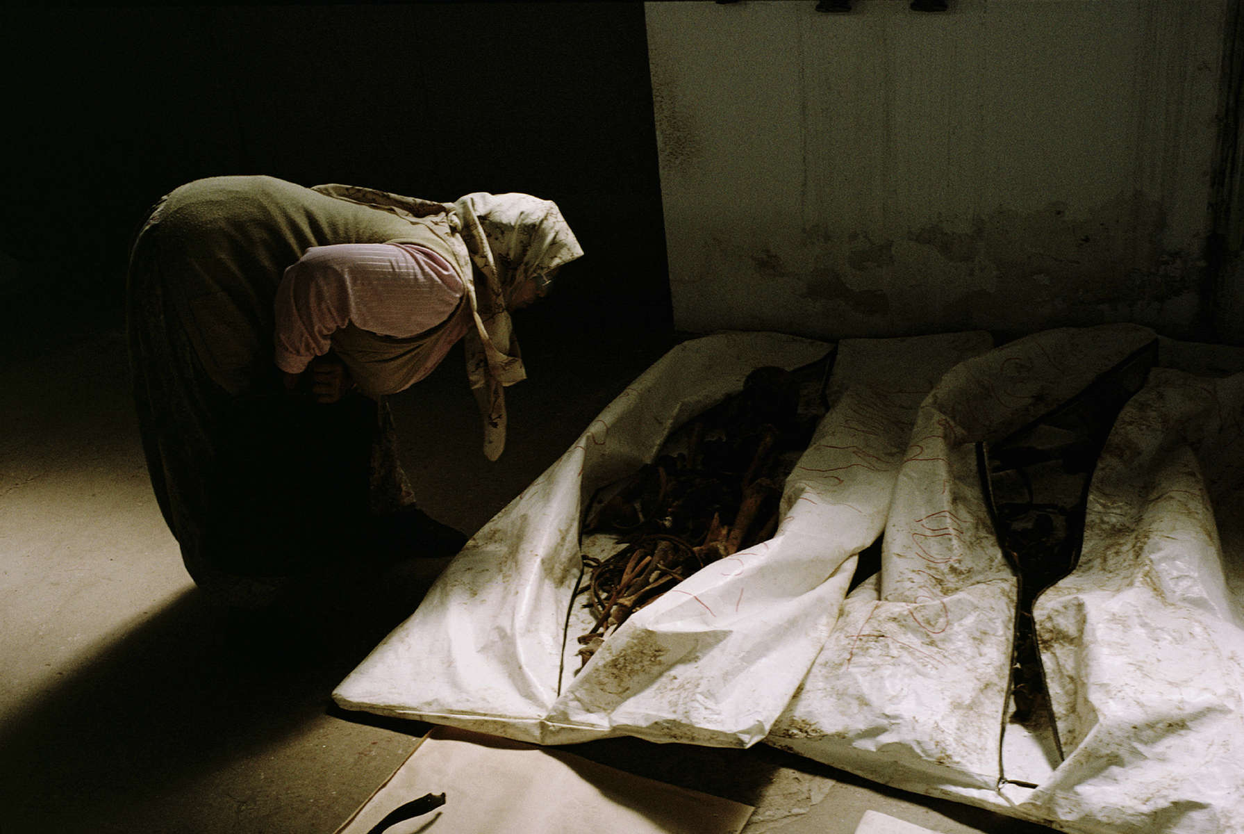 Muslim widow examines body bags containing the remains of recently exhumed victims of the 1992 \{quote}ethnic cleansing\{quote} campaign waged by Serbs against their Muslim neighbors. Exhumations of mass graves began in 1996 and are expected to last for many years to come. Nearly 30,000 Muslims -- most of them civilians -- were listed as missing at the end of the war; most are believed to have been victims of \{quote}ethnic cleansing.\{quote} July 2001