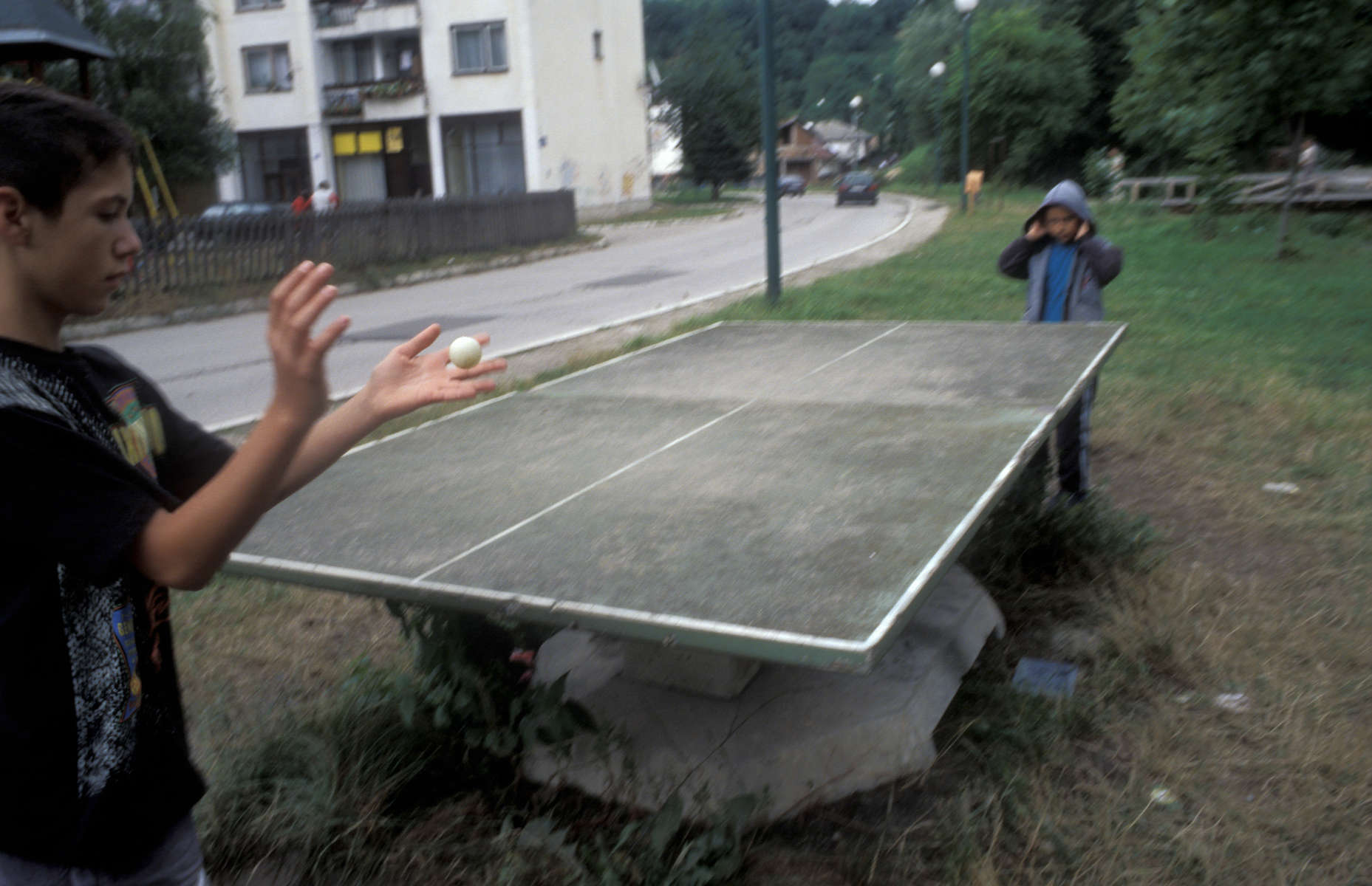 Two boys play a makeshift game of ping pong, with no net and no paddles. 