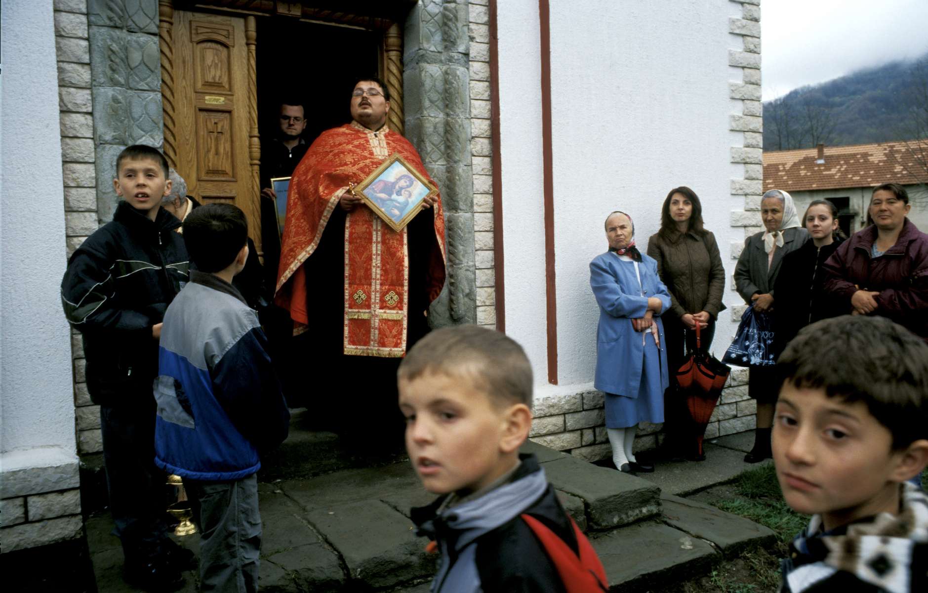 A Serb Orthodox priest holds an icon being auctioned to parishioners, who pay to carry the icons in a small procession that circles the church three times on Orthodox Easter Sunday. The church was damaged by extremist mujahideen who came to fight in Bosnia during the war, but was restored in recent years.