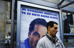 At a bus stop in Sarajevo, an election poster for the moderate \{quote}Stranka za BiH\{quote} party (Party for Bosnia Hercegovina) reads, in rough translation, \{quote}Through investment, to new jobs.\{quote} The slogan is a reference to the country\'s troubled economy, and its unemployment rate of nearly fifty percent. The man in the poster is Haris Silajdzic, who served as prime minister during the war. In this election, all the moderate parties were defeated, as voters returned nationalist parties to power. September 2002.