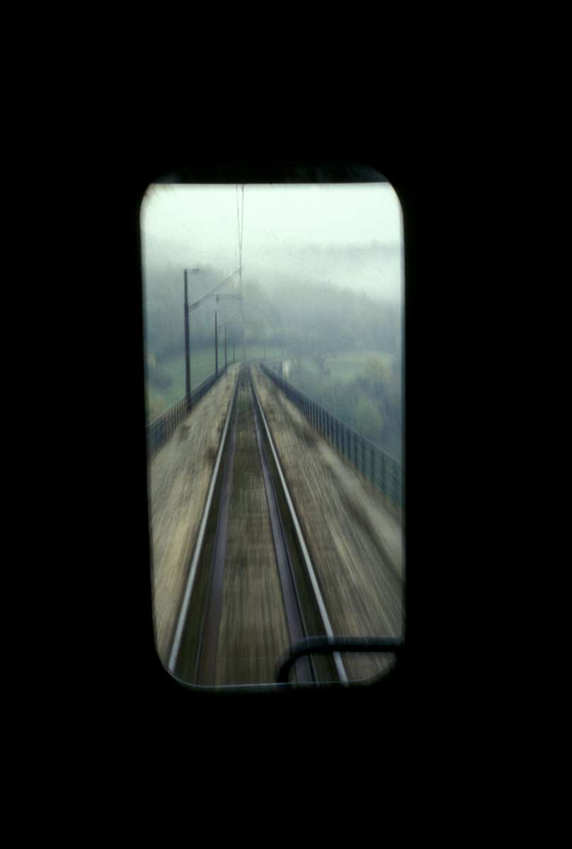 Window reflection from a one-car passenger train that runs between Sarajevo and the town of Konjic, about forty-five minutes to the south. Before the war, the former Yugoslavia had one of the best rail transit systems in Europe. Bosnia\'s rail system was virtually entirely destroyed during the war and is only slowly being rebuilt.