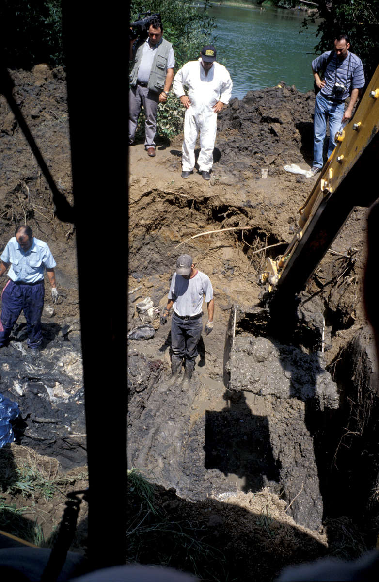 A steam shovel removes mud and dirt from a site identified as a mass grave, thanks to a tip from a Serb informant. Exhumation officials say that as more time passes since the end of the war, Serbs are increasingly offer information -- often anonymously -- about where to find mass graves. Many of the informants say they want to clear their consciences, according to authorities. This exhumation of this grave yielded about two dozen remains. July 2000.
