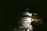 A family member looking for remains of a loved one reaches toward bones in a body bag, during a public viewing of exhumed remains. July 2001.
