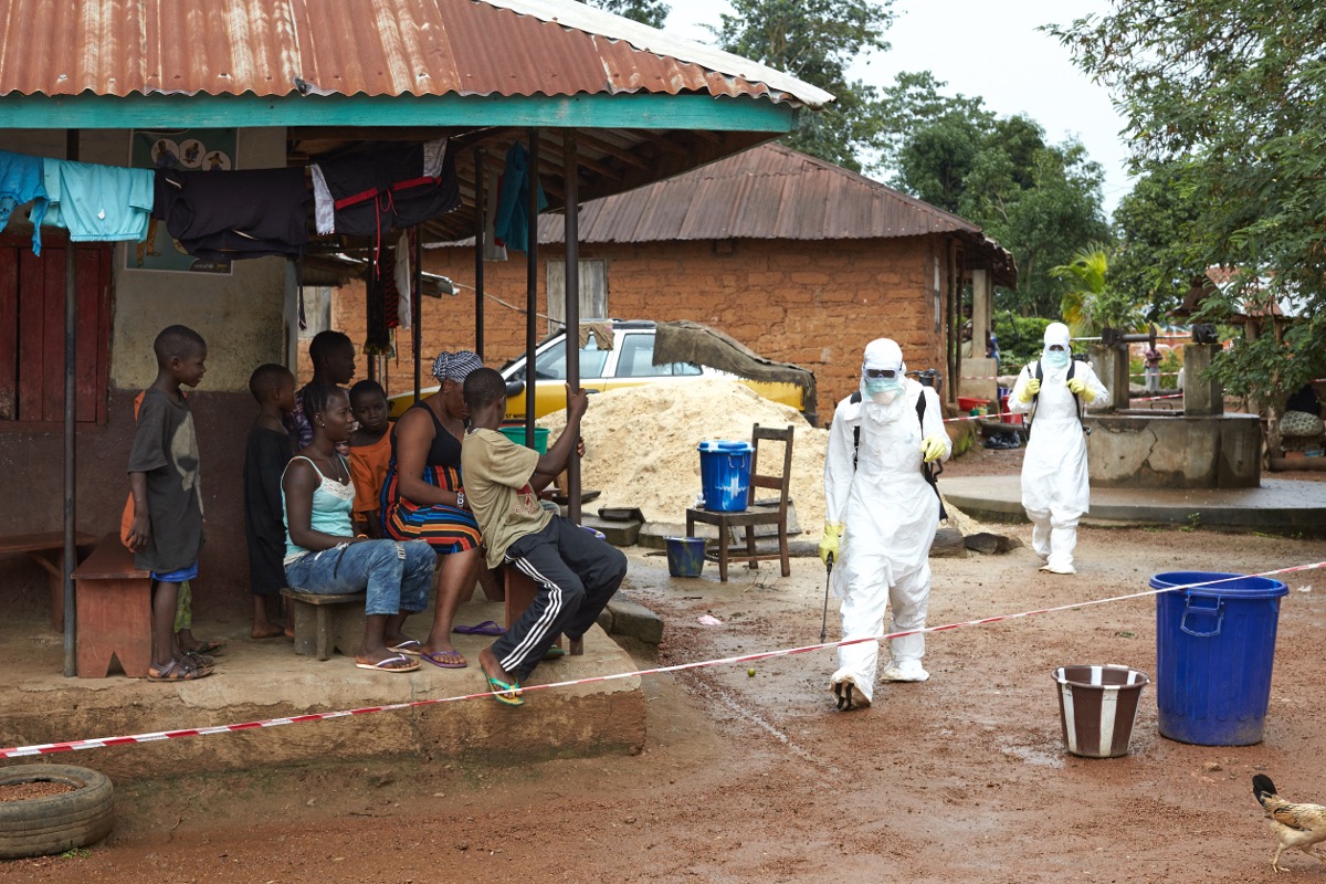 A decontamination team moves between houses in Tonkolili, Sierra Leone