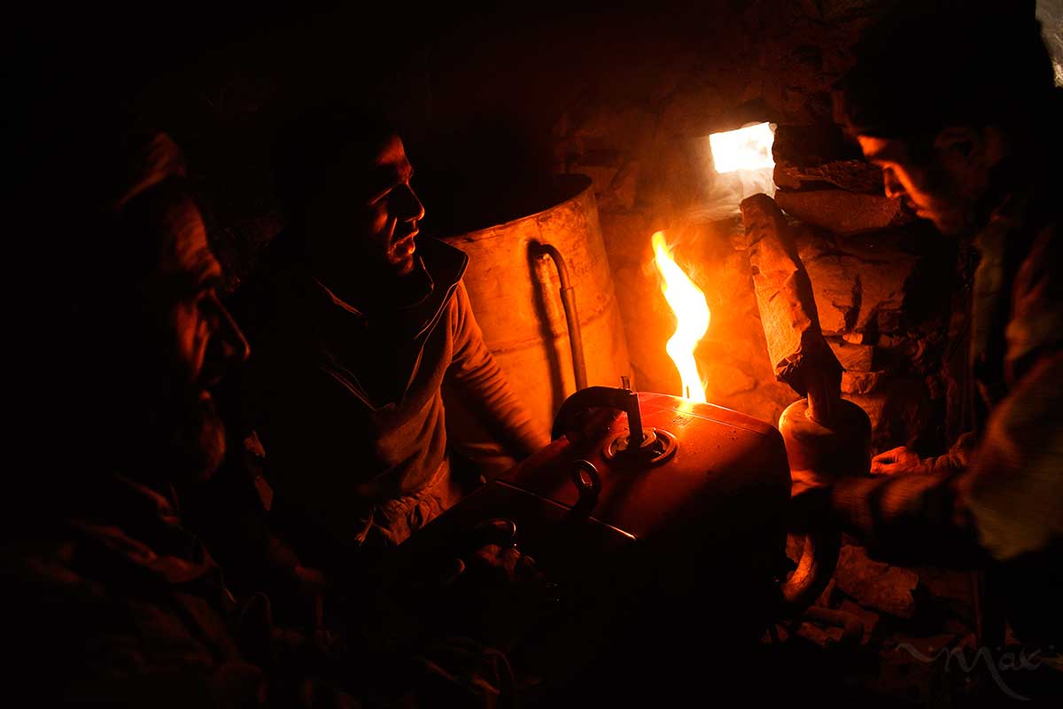 October 25, 2007- Khenj, Afghanistan: Ahmad Jawead, 22, center works with the mechanic of the mountain, Mohammad Israar, 46, left, and his hired hand  Rahimullah, 27, as they try to start a Chinese made motor that creates compressed air for his air pressure operated rock drill in the mountains over the Panjshir Valley village of Khenj, Afghanistan on Thursday October 25, 2007. The motor has a hand crank but they hope by heating up the carburetor they can help to prime the start. 