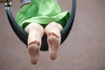 a girl's feet as she swings on the playground in Hoboken