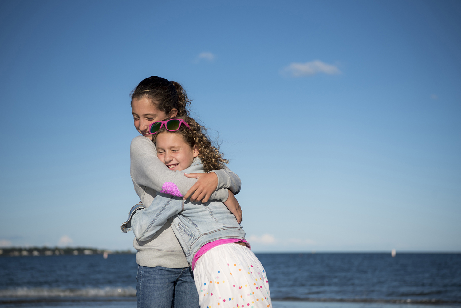 sisters embrace on beach at Tod's Point in Greenwich, CT