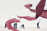 Red fabric dragons dance in the foreground with blurred Conemen standing on a beach in the background