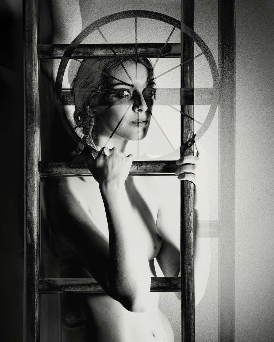 vintage style black and white nude woman solarised image in surreal style behind a ladder
