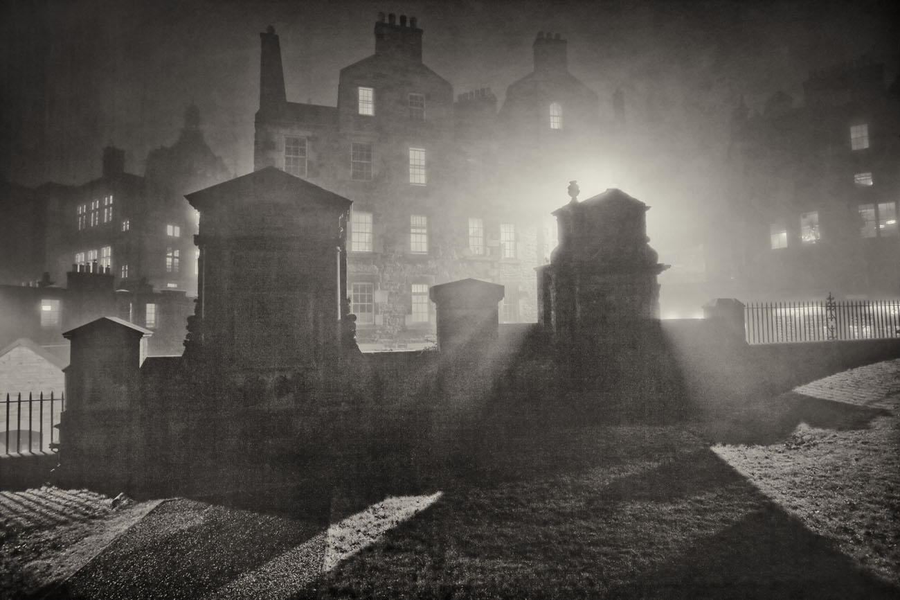 light filtering through the fog onto gravestones in Greyfriars Kirk at night.