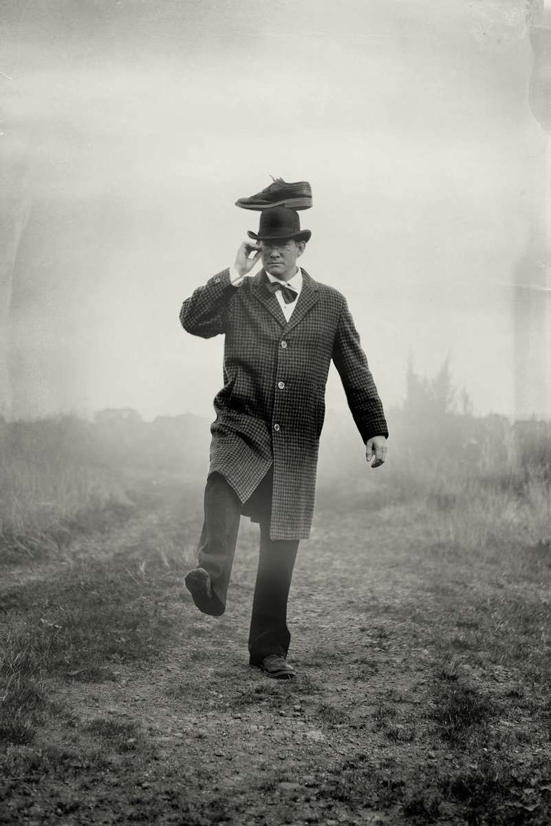 vintage image of a man walking with a shoe on his head.