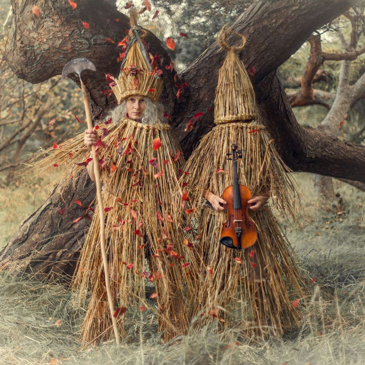 two women skeklers in a forest with red leaves falling. Skekler with a fiddle