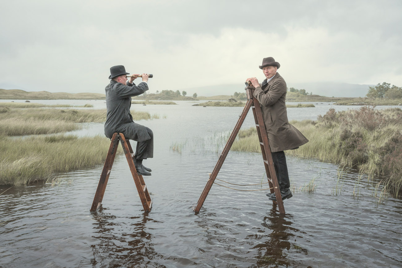 surreal Photograph of two men sitting on ladders in rannoch moor loch in Scotland
