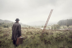 A man walks towards a floating ladder in a misty Scottish landscape