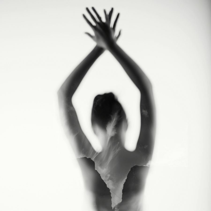 blurred nude double exposure of a woman with her hands raised