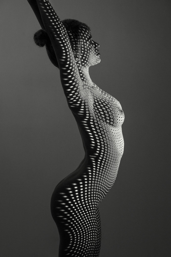 Nude B+W woman with projected dots in the studio