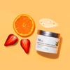 InstaNatural's Brightening Vitamin C Scrub photographed on orange with the natural ingredients of strawberry and citrus and a swatch.