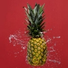 Pineaple and water splash against a red background. Photographed for Seagram's Hard Seltzer.