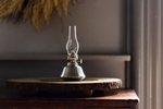 A pewter oil lamp sitting on a nightstand with moody lighting. Photographed for the April Cornell catalog.