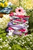 A stack of tea towels rest amongst flowers. Homegood catalog photography for April Cornell.