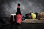 Magic Hat Brewing beer Duvine Rouge Ale on tabletop with a glass, pear, grapes and loaf of bread.