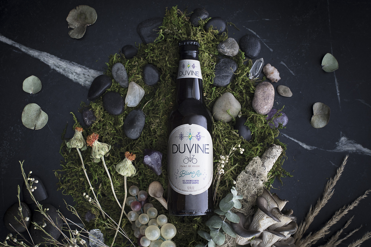 Magic Hat Brewing beer Duvine Blanc Ale on tabletop with natural props.