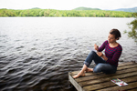 Young woman drawing on dock near lake water, by Vermont photographers at Reciprocity Studio, Burlington