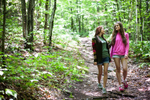 Two young women walking through forest. by Vermont photographers at Reciprocity Studio, Burlington