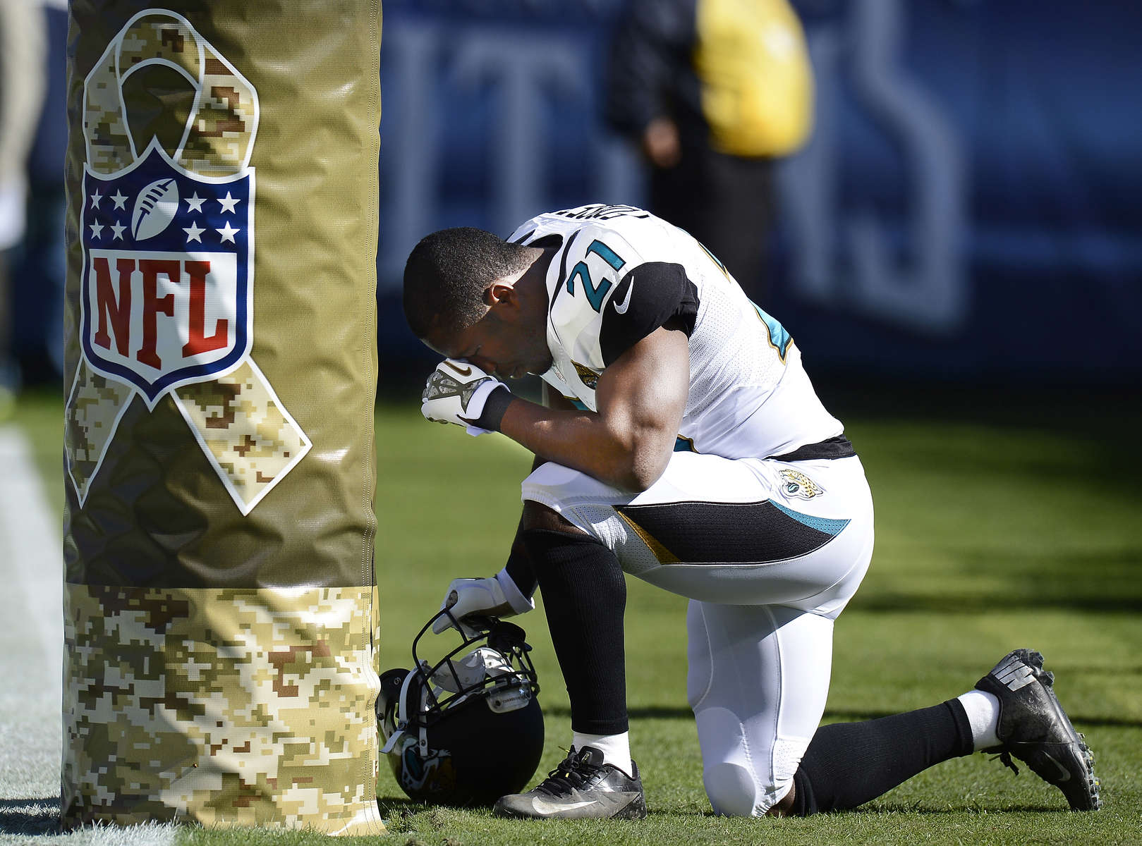 Jacksonville Jaguars running back Justin Forsett kneels by a Salute to Service logo on a goal post before an NFL football game between the Jaguars and the Tennessee Titans on Nov. 10, 2013, in Nashville, Tenn. (AP Photo/ Mark Zaleski)