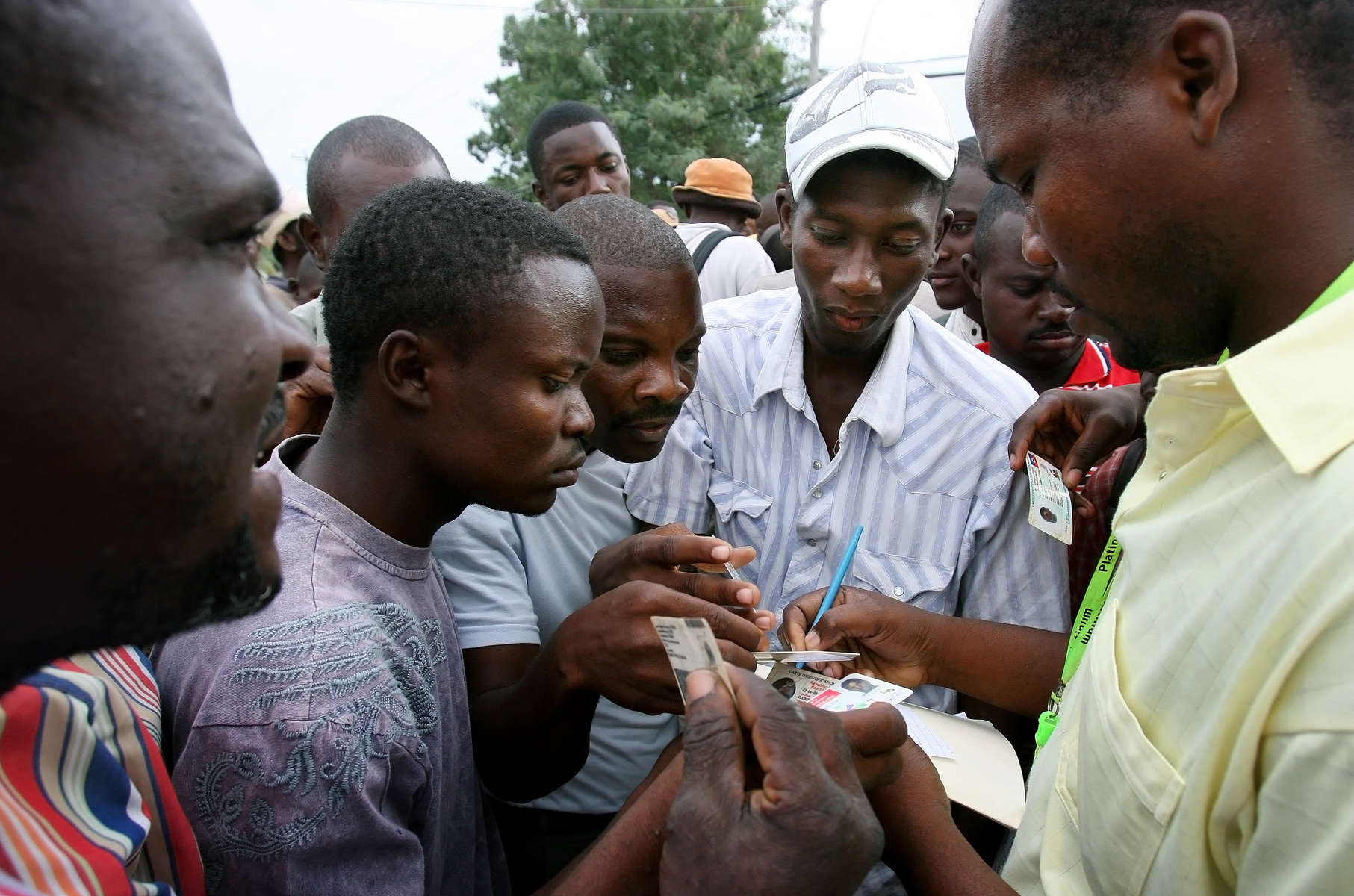 Haitian men gather around a man distributing identification cards needed to get work assisting in the humanitarian aid effort at Port-Au-Prince International Airport in Haiti. (The Press-Enterprise/ Mark Zaleski)