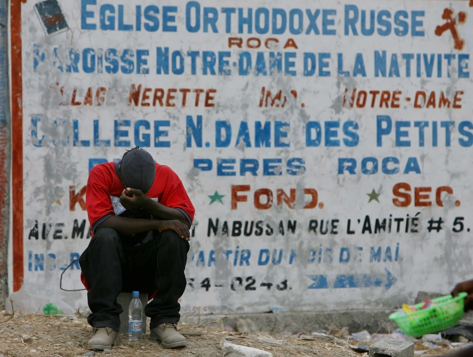 A Haitian man sits near the entrance to Port-Au-Prince International Airport hoping to get work transporting or distributing aid supplies. (The Press-Enterprise/ Mark Zaleski)