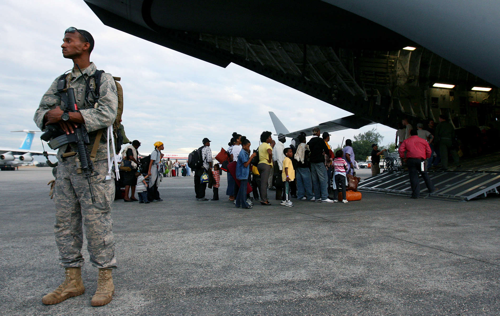 A United State Air Force security guard monitors the March Air Reserve Base C-17 aircraft while the crew boards evacuees at Port-Au-Prince International Airport in Haiti. (The Press-Enterprise/ Mark Zaleski)