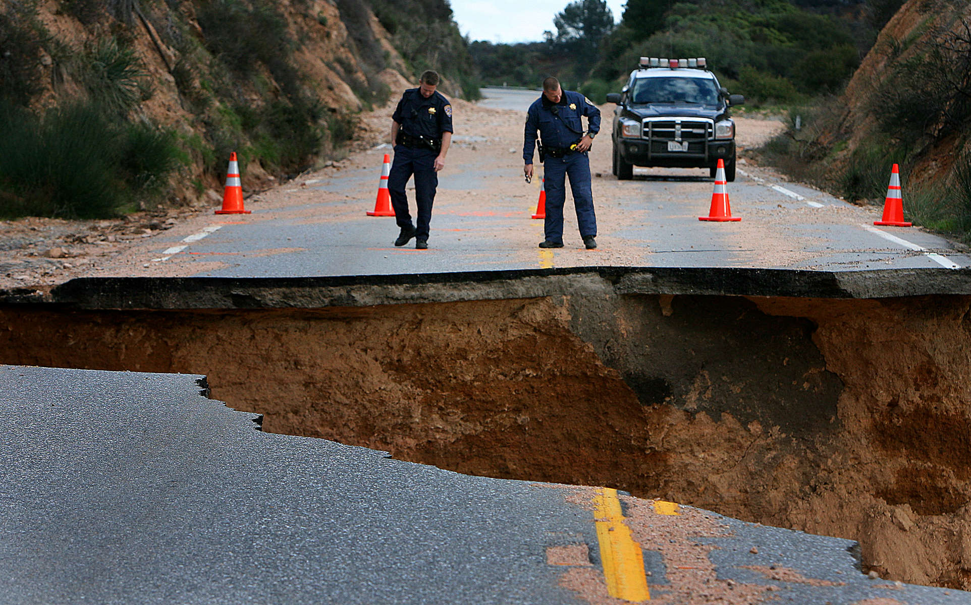 California Highway Patrol officers inspect a section of Highway 330 in the San Bernardino Calif., mountains after it was washed away during a rain storm. (The Press-Enterprise/ Mark Zaleski)