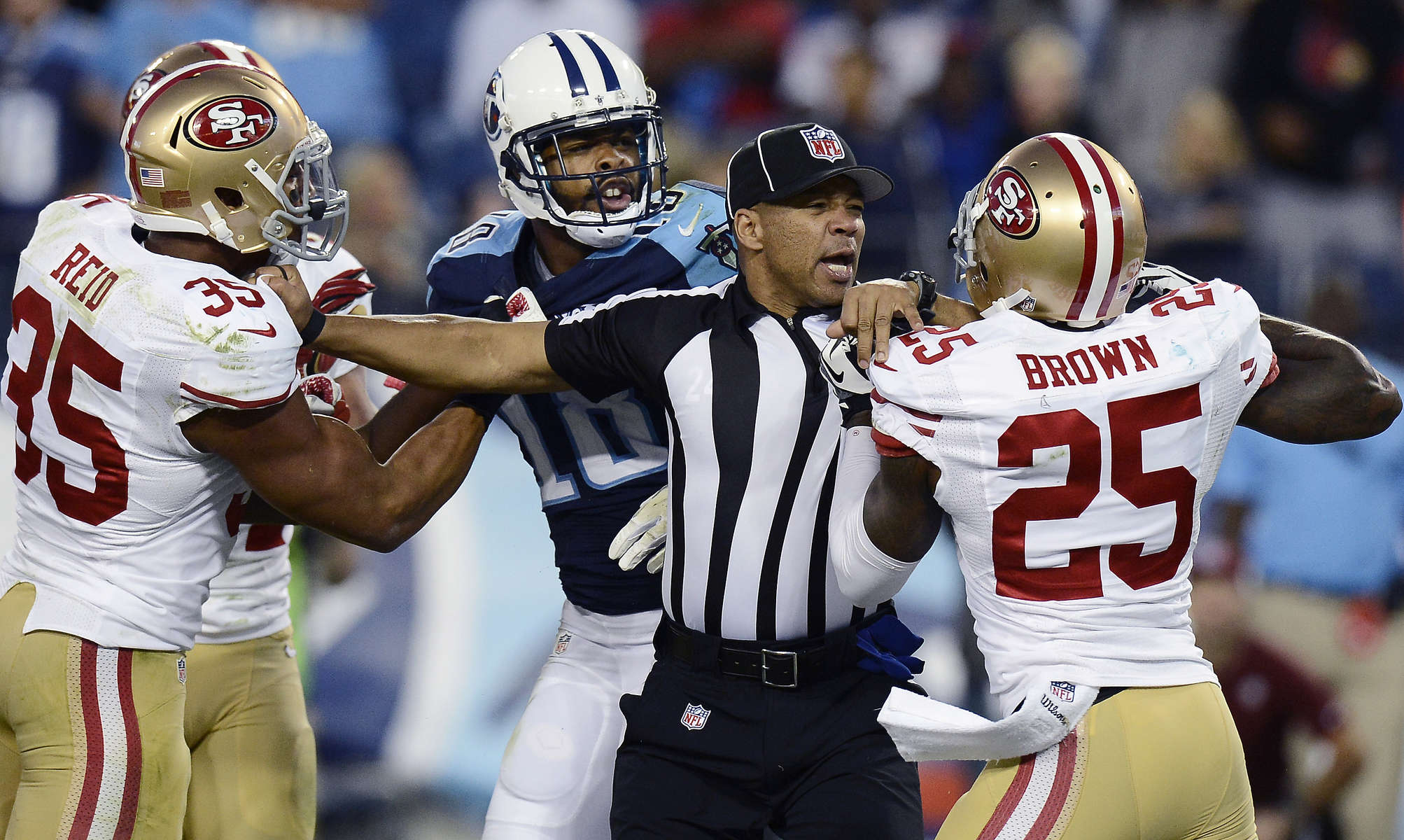 Back judge Greg Steed tries to separate San Francisco 49ers cornerback Tarell Brown and Tennessee Titans wide receiver Kenny Britt during a scuffle in the fourth quarter of an NFL football game on Oct. 20, 2013, in Nashville, Tenn. At left is 49ers Eric Reid.(AP Photo/ Mark Zaleski)