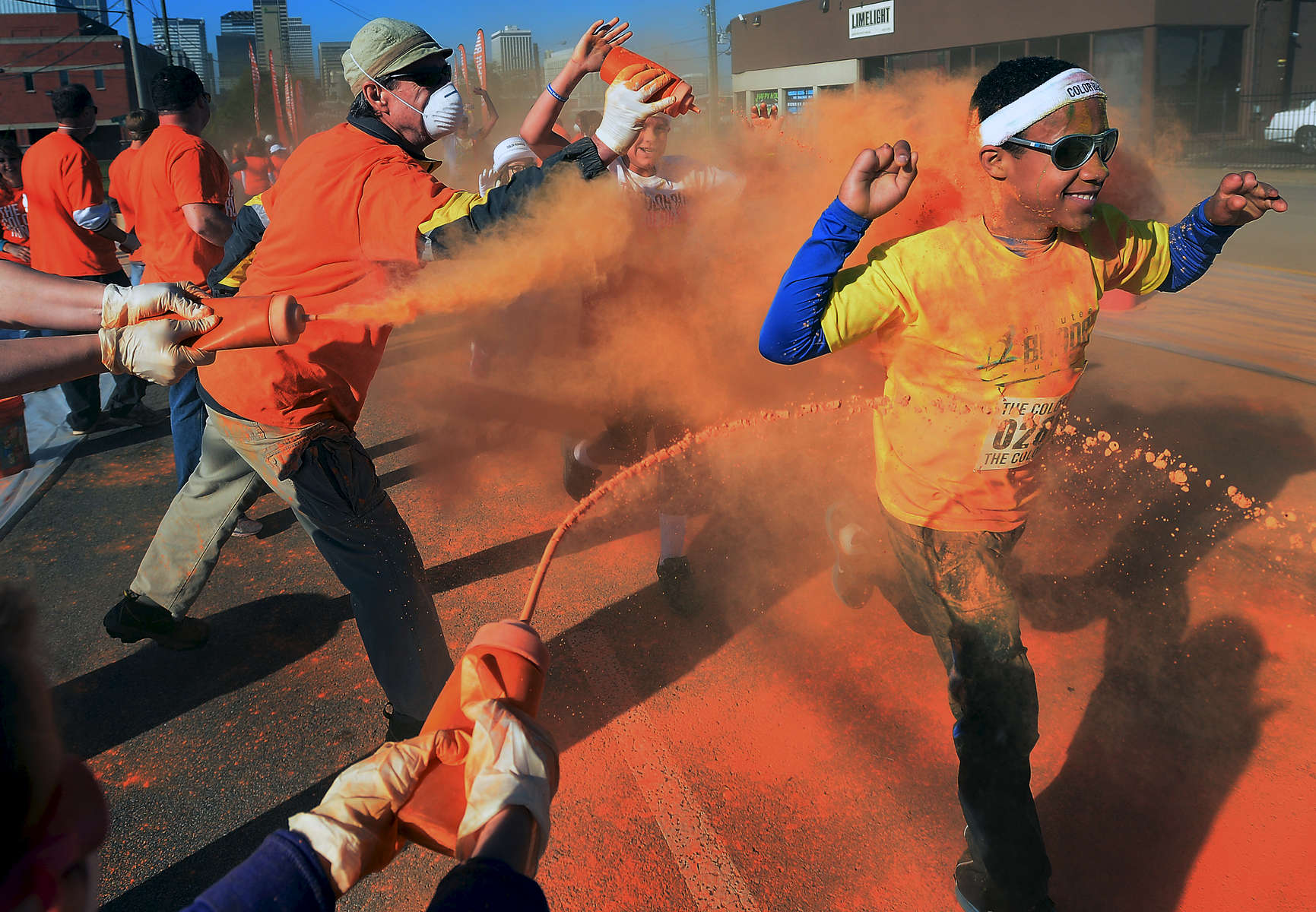 Tommy Barnes is sprayed from three directions by volunteers with powder at the orange color zone along Woodland Street during the 5K Color Run in Nashville, Tenn. (Mark Zaleski/ For The Tennessean)
