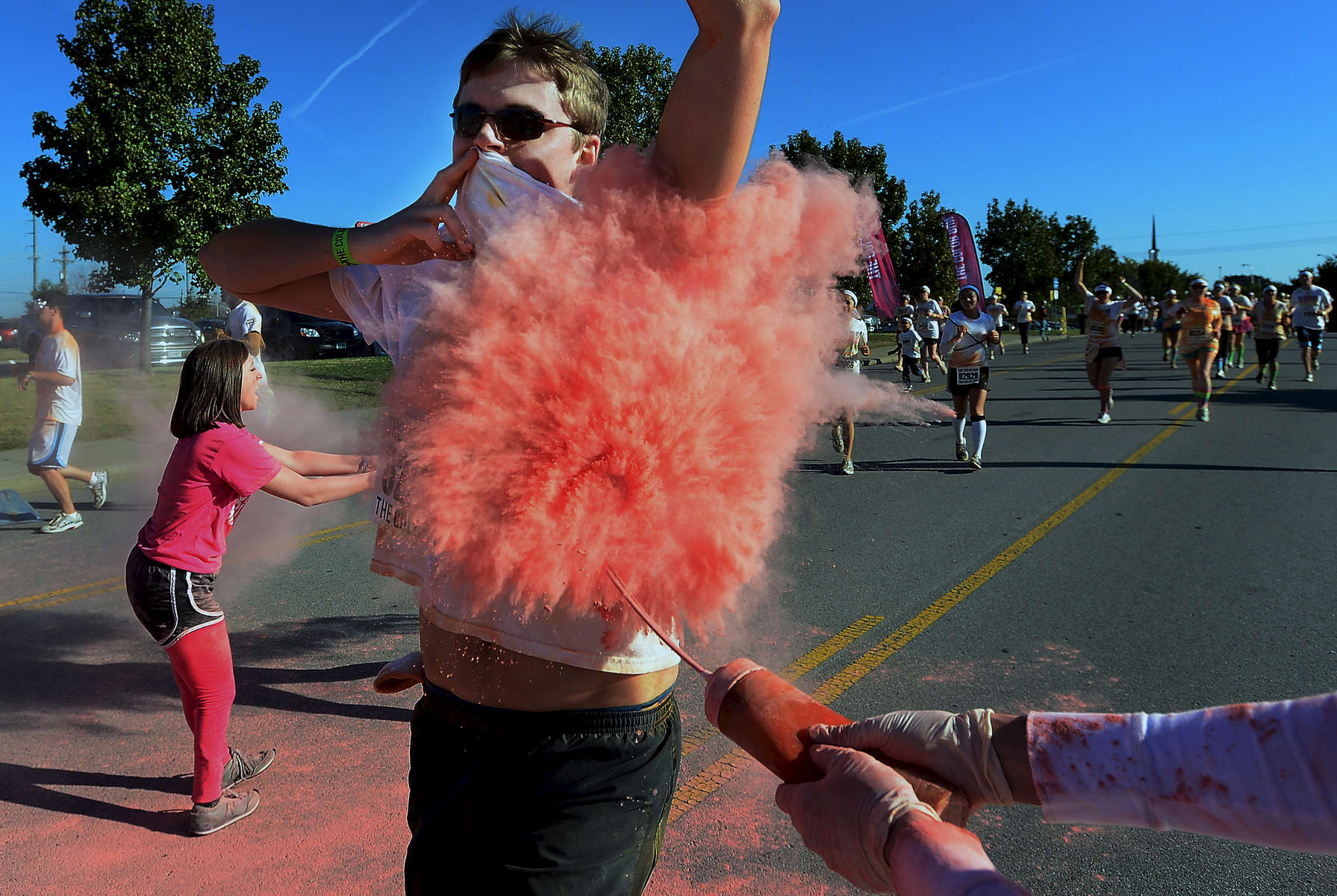 A participant covers his mouth while being sprayed with pink powder at the 3K mark along Russell Street during the 5K Color Run in Nashville, Tenn (Mark Zaleski/ For The Tennessean)