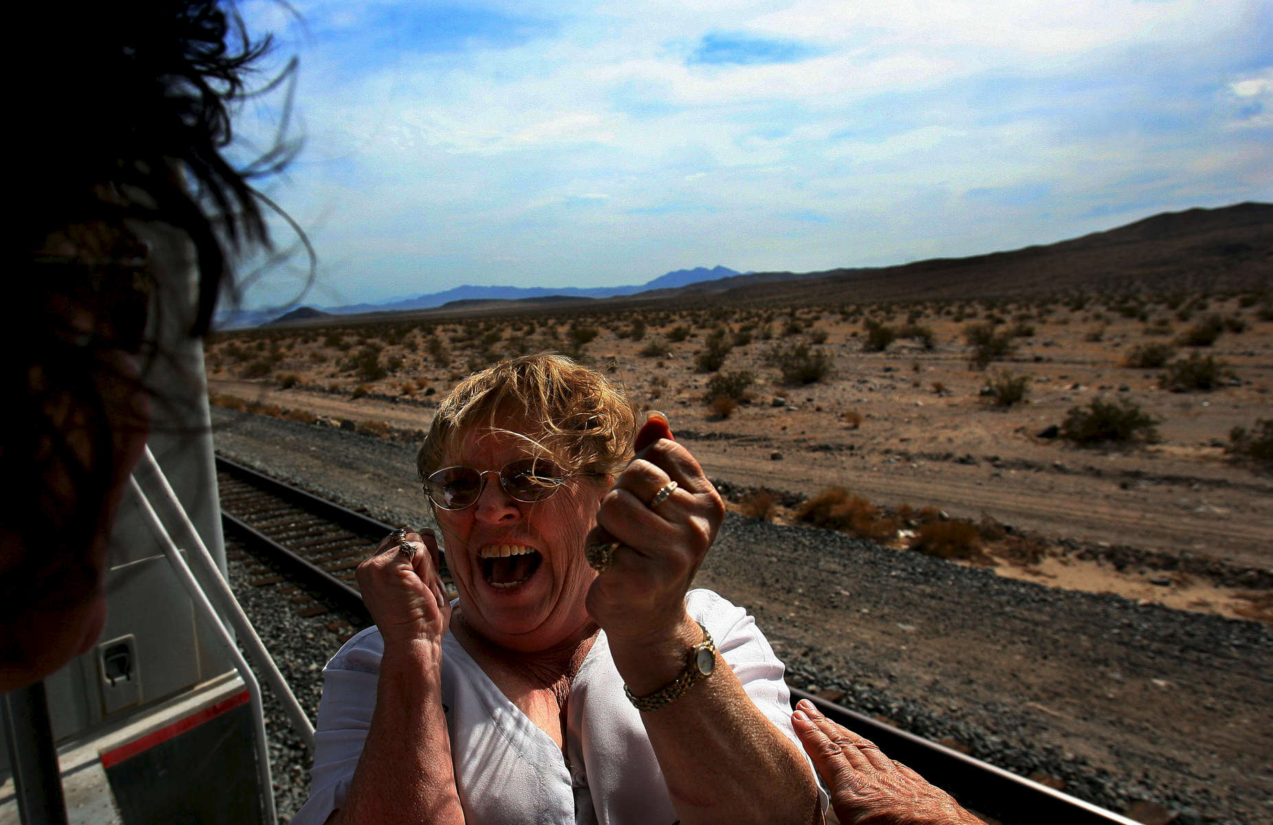 Carol Randall, a co-coordinator of the Kelso Flyer, is overwhelmed with emotion, turning to Marcia Bond and belting out, {quote}We did it{quote}, as they view the Mojave National Preserve from the rear plantform of the Tioga Pass rail car during the Kelso Flyer train ride. (The Press-Enterprise/ Mark Zaleski)