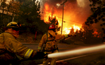 Firefighters spray water on a house trying to protect it while several other homes burn along Brentwood Lane in Lake Arrowhead, Calif., during the Old Fire. (The Press-Enterprise/ Mark Zaleski)