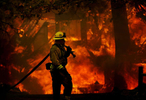 A firefighter moves his hose line away from a burning house along Brentwood Lane while battling the Grass Valley Fire in Lake Arrowhead, Calif. (The Press-Enterprise/ Mark Zaleski)