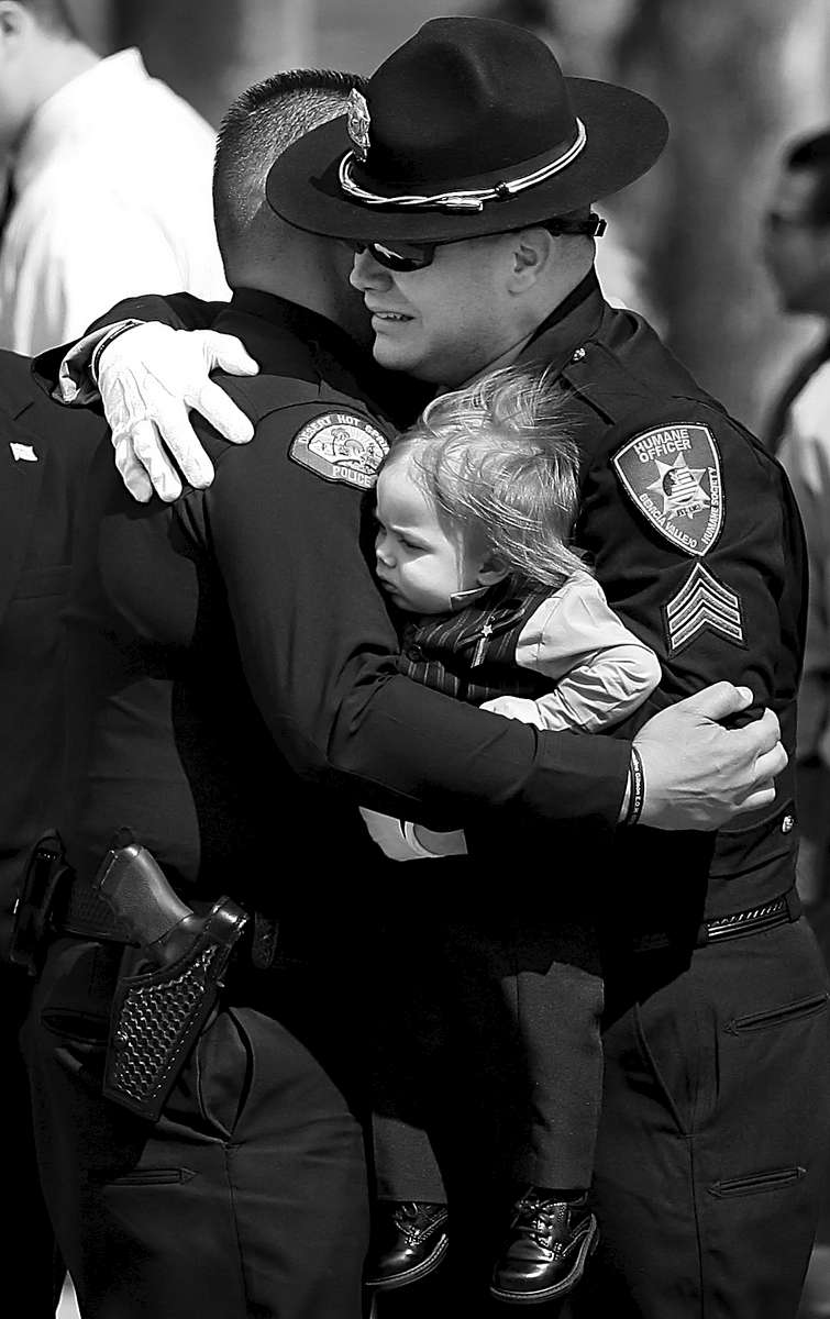 Benicia Vallejo Humane Officer Brian Brisco holds his son as he grieves while being consoled at the memorial service of his best friend, Cathedral City Police Officer Jermaine Gibson, at the Riverside National Cemetery in California. Gibson was killed during a police pursuit. (The Press-Enterprise/ Mark Zaleski)
