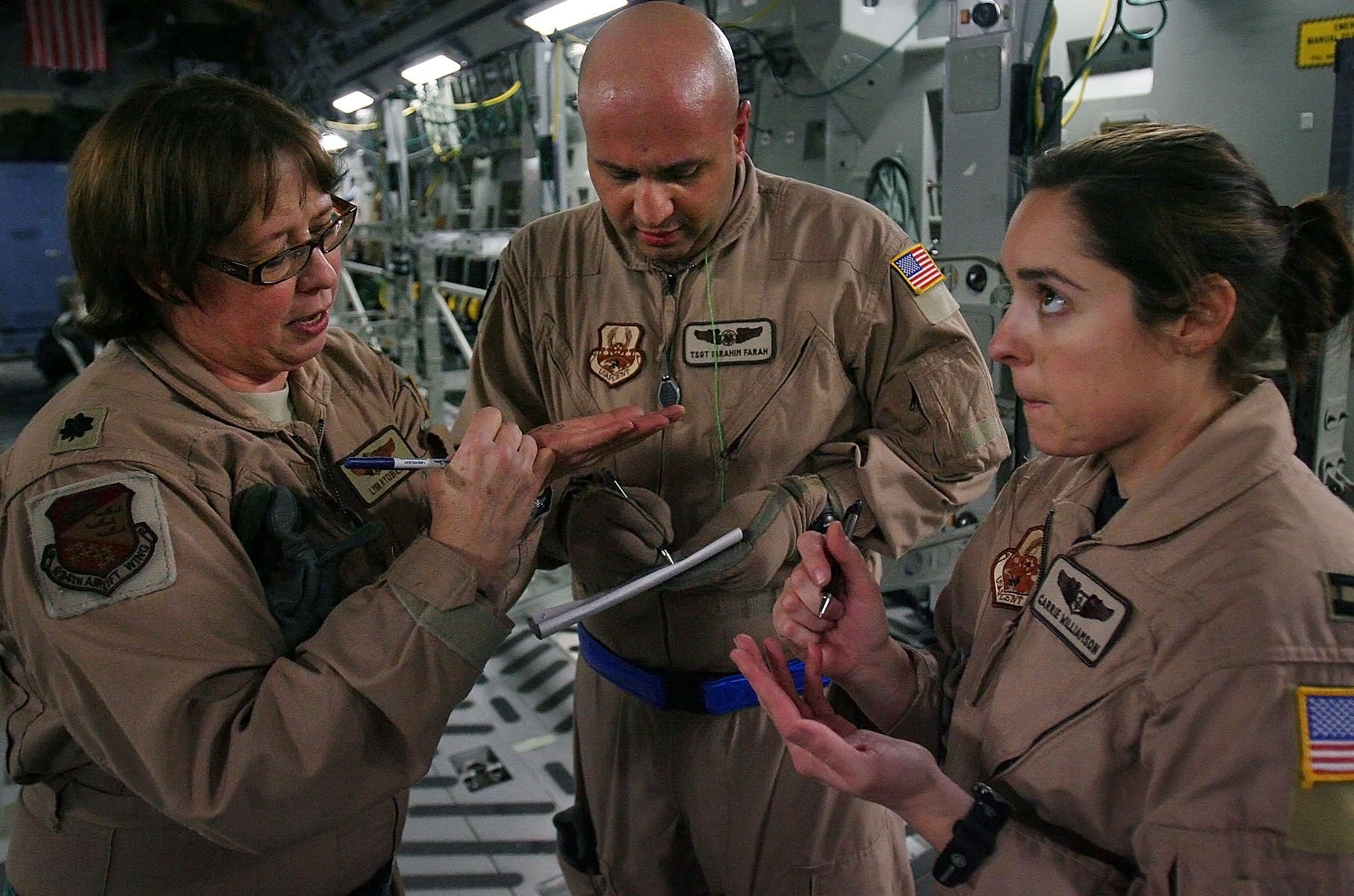 Lt. Col. Lynn Rydberg from Minneapolis Air Reserve Station, left, Medical Technician Ibrahim Farah and Medical Technician Cpt. Carrie Williamson from Peterson Air Force Base in Colorado calculate by writing on their hands how many litters to set up for inside the March Air Reserve Base Globemaster C-17. The aircraft's cargo bay is transformed into an air hospital, moving wounded warriors from Bagram Air Force Base in Afghanistan to Ramstein Air Force Base in Germany for more medical care.(The Press-Enterprise/ Mark Zaleski)