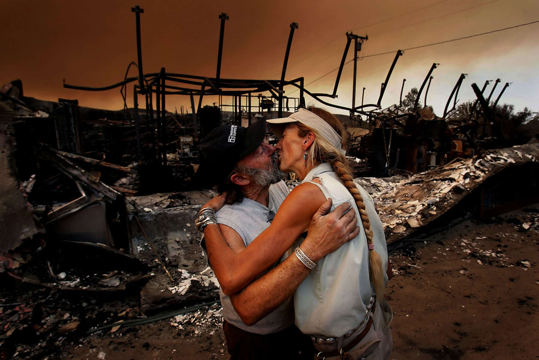 Bruce Milne, left, comforts his wife, Melanie, after his metal shop was destroyed by the Sawtooth Fire. Their home on Lariat Trail was spared by the fire storm that hit Pioneertown in Yucca Valley, Calif. The firedestroyed more than 50 homes and buildings. (The Press-Enterprise/ Mark Zaleski)