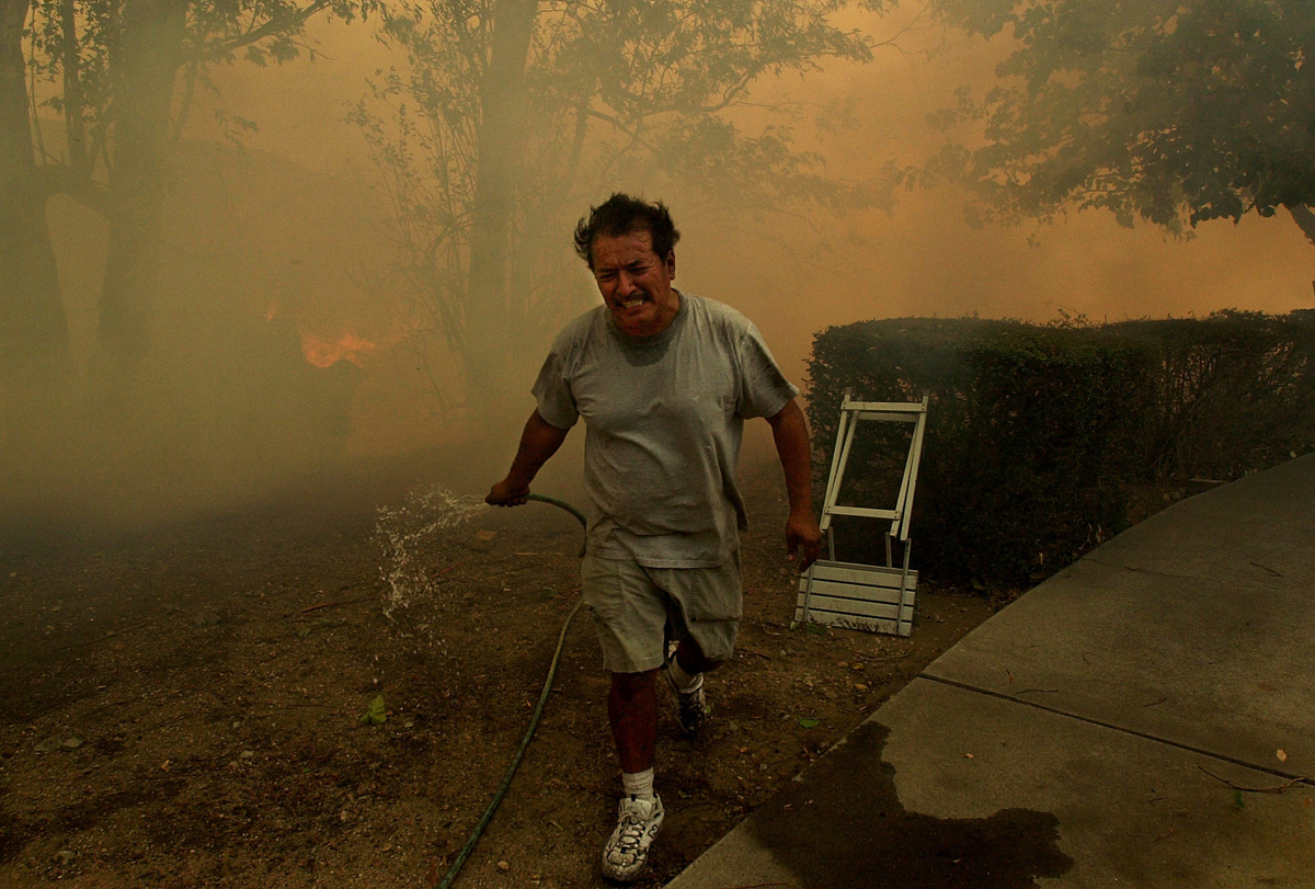 Joe Botello runs away from smoke and flames approaching his house on 54th Street in SanBernardino, Calif. Botello returned days later to find that his house was destroyed in the Old Fire. (The Press-Enterprise/ Mark Zaleski)