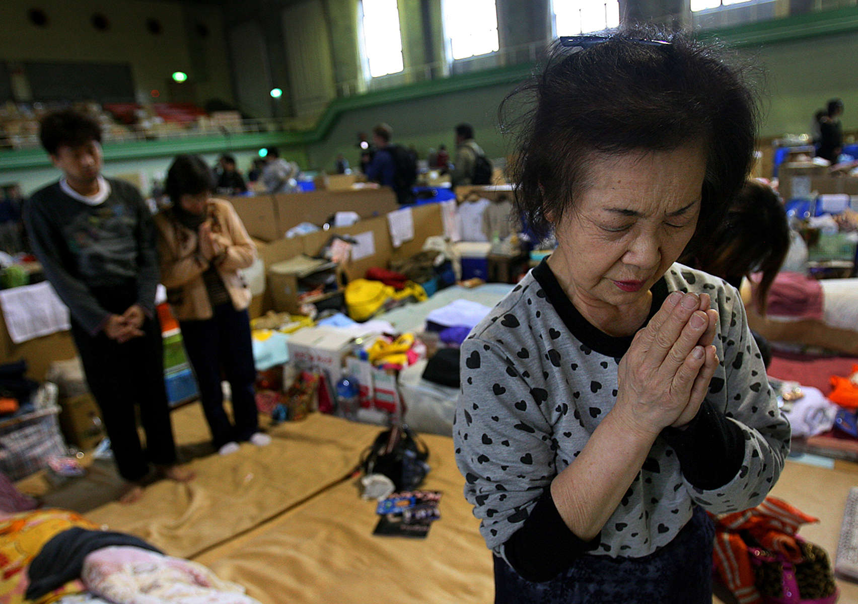 Kimiko Daigaku, 68, prays during a moment of silenceat the Wakabayashi Gym in Sendai on the one month anniversity of the earthquake and tsunami that hit Japan at 2:46 p.m. March 11, 2011. She is one of 320 evacuees living in the gym since their homes were destroyed in a 9.0 earthquake and tsunami. (The Press-Enterprise/ Mark Zaleski)