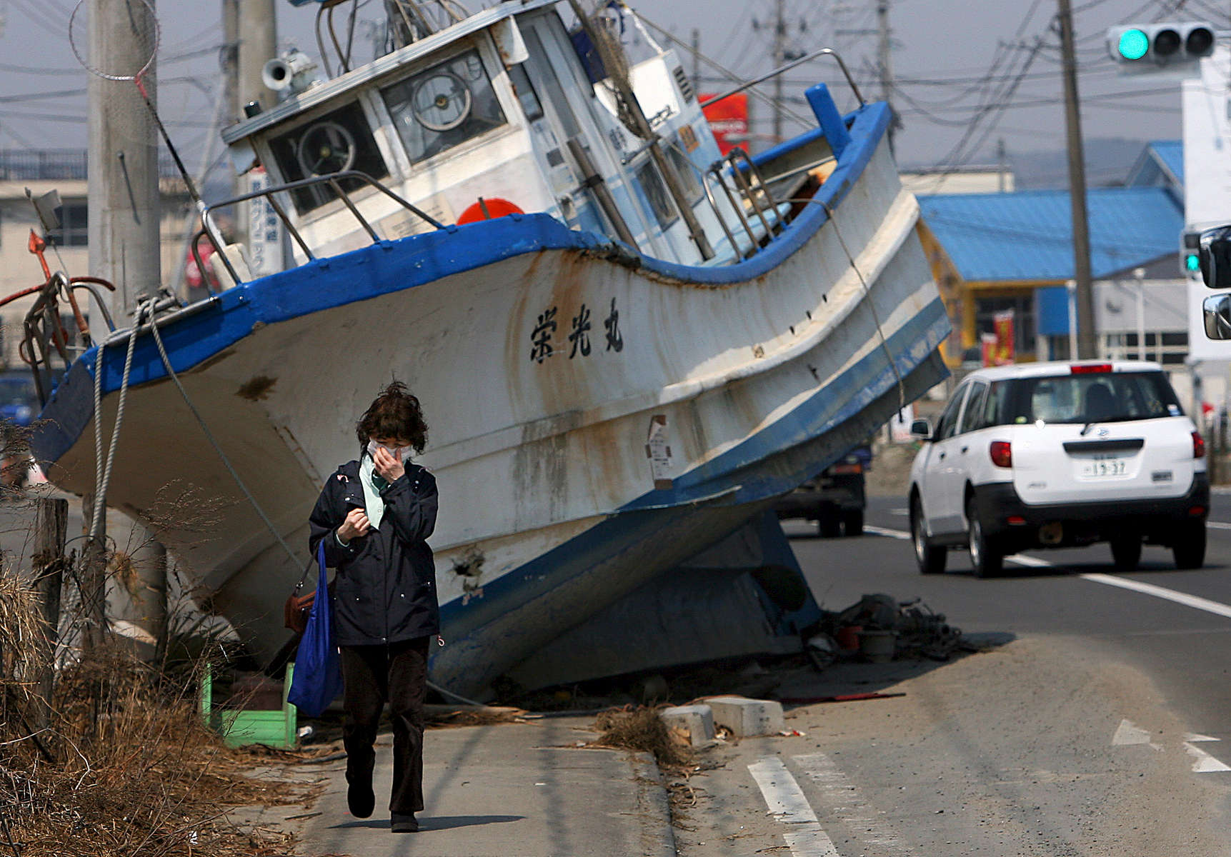 A woman walks past a fishing boat that washed ashore in Shichigahama, a fishing town of northern Sendai, Japan. (The Press-Enterprise/ Mark Zaleski)