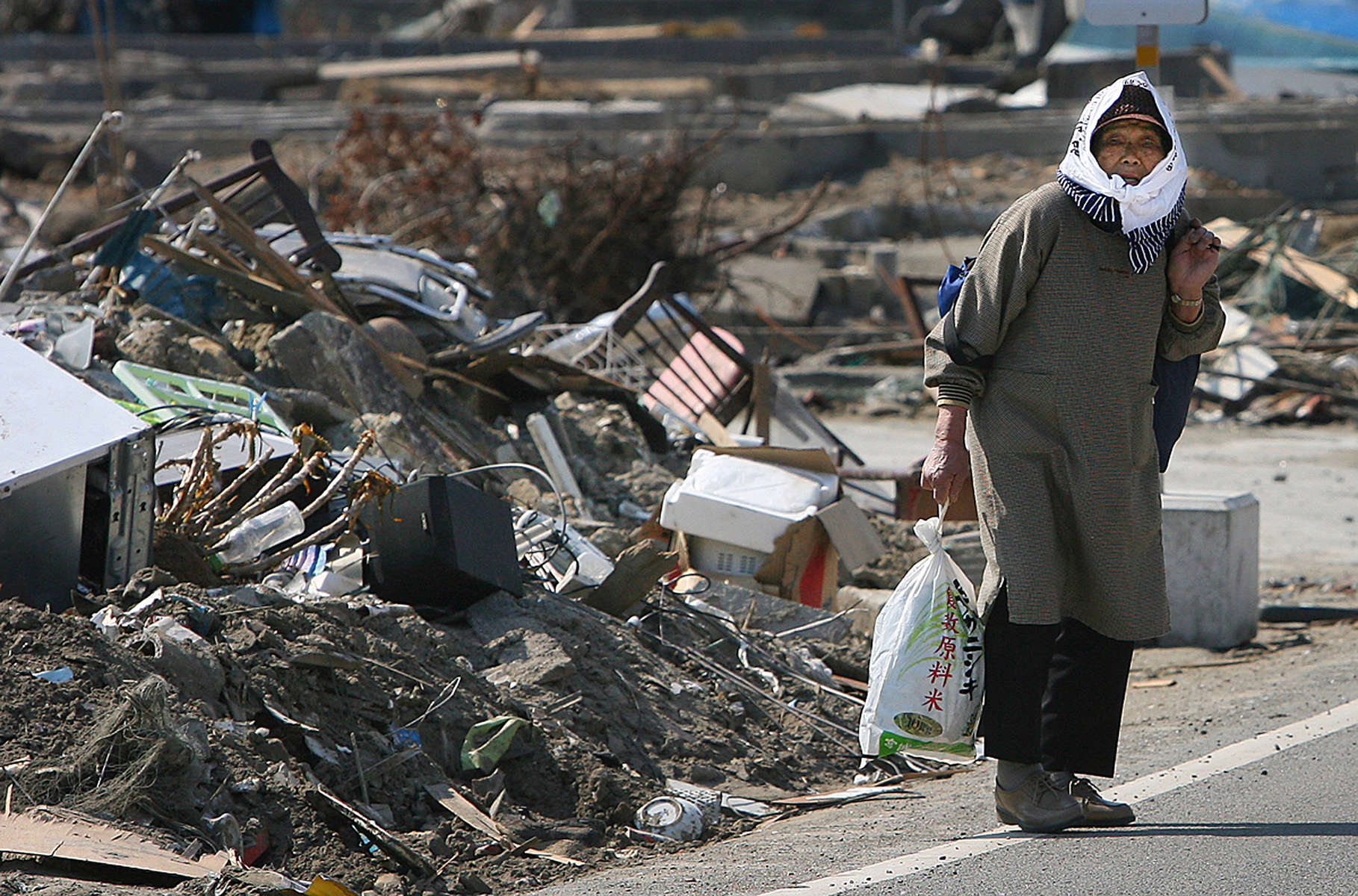 A woman carries supplies she bought at a convenience store miles away from her destroyed home in Shichigahama, a fishing town of northern Sendai, Japan. (The Press-Enterprise/ Mark Zaleski)