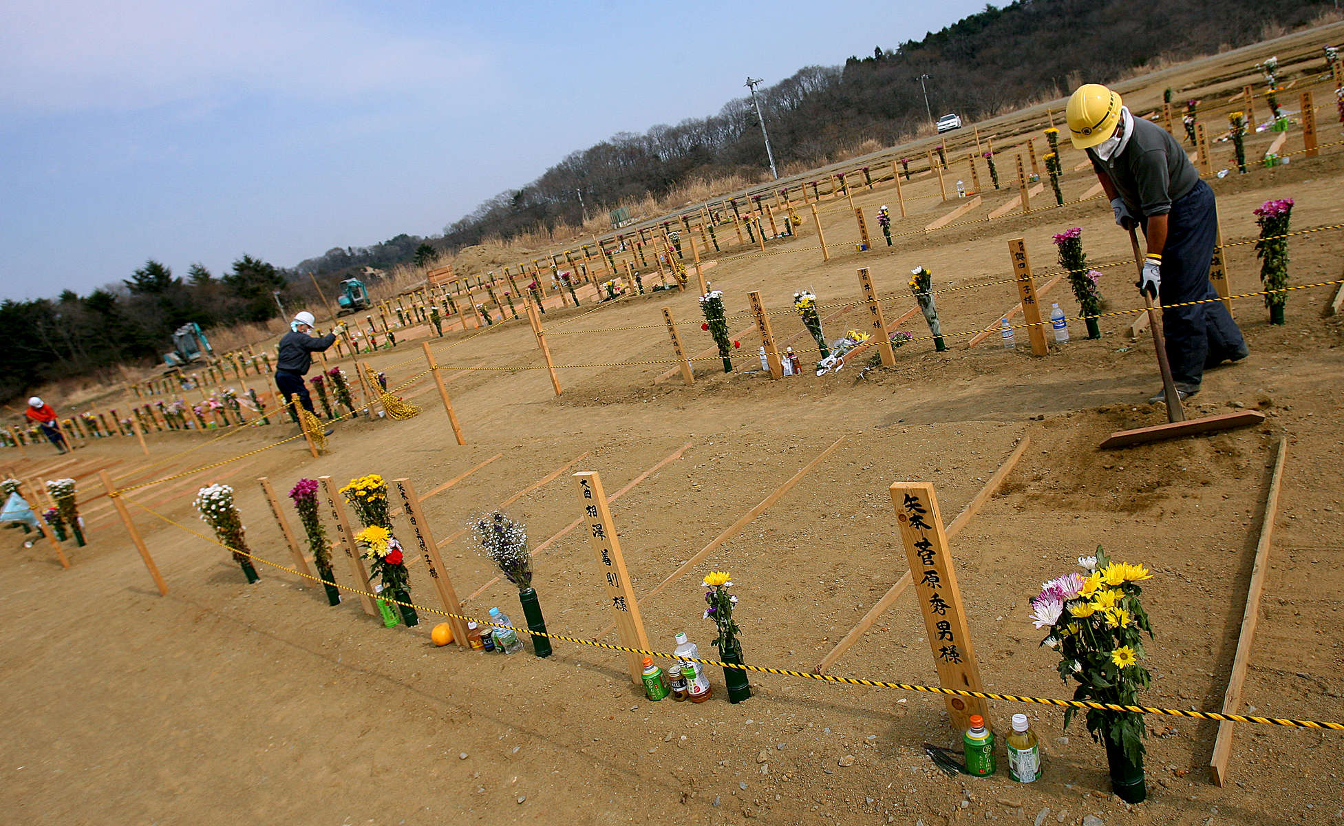 Gravesite workers carefully level out the dirt as they attend to a temporary burial site near a recycling center in Higashimatsushima, a ward of Sendai, Japan. (The Press-Enterprise/ Mark Zaleski)