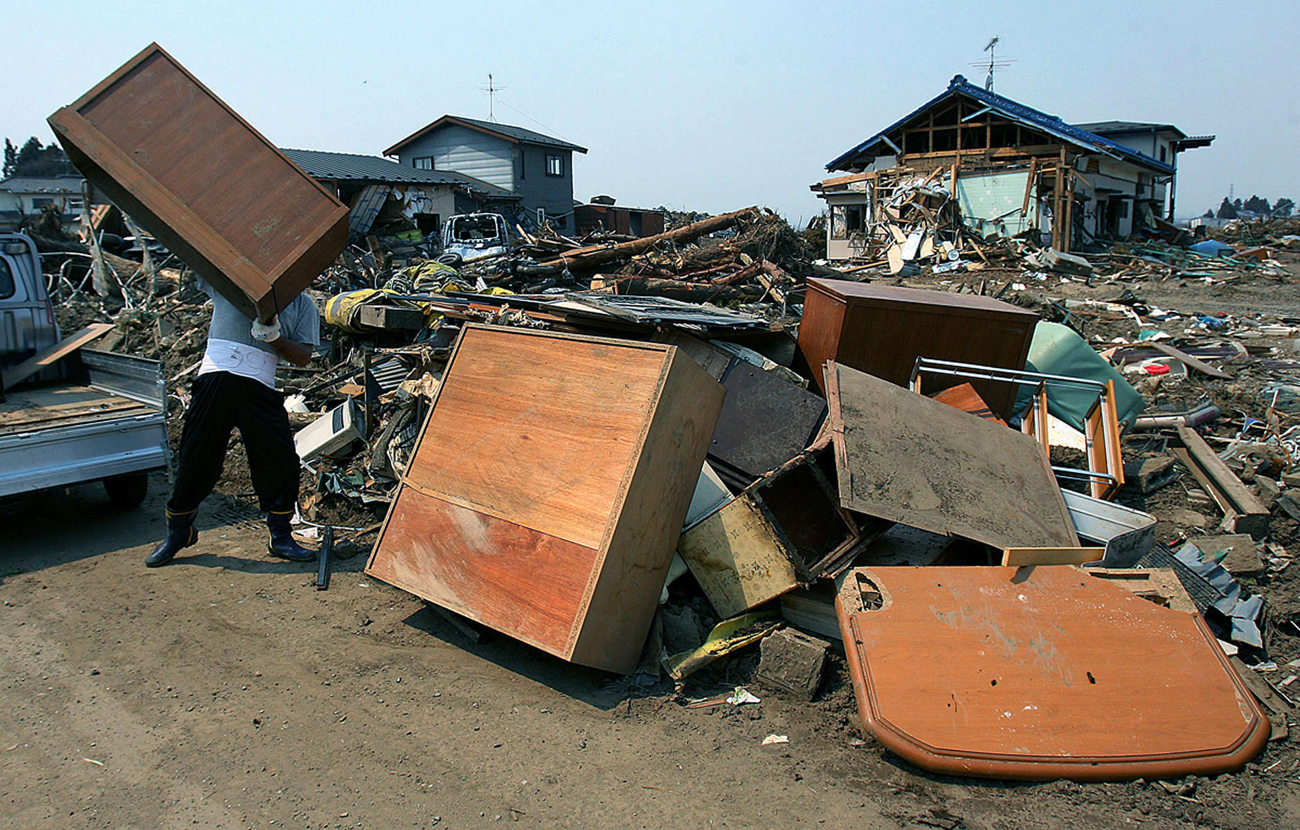 Shusuka Kikushi lifts a dresser onto a pile of damaged furniture while cleaning out his friend's destroyed homein Sendai, Japan. (The Press-Enterprise/ Mark Zaleski)